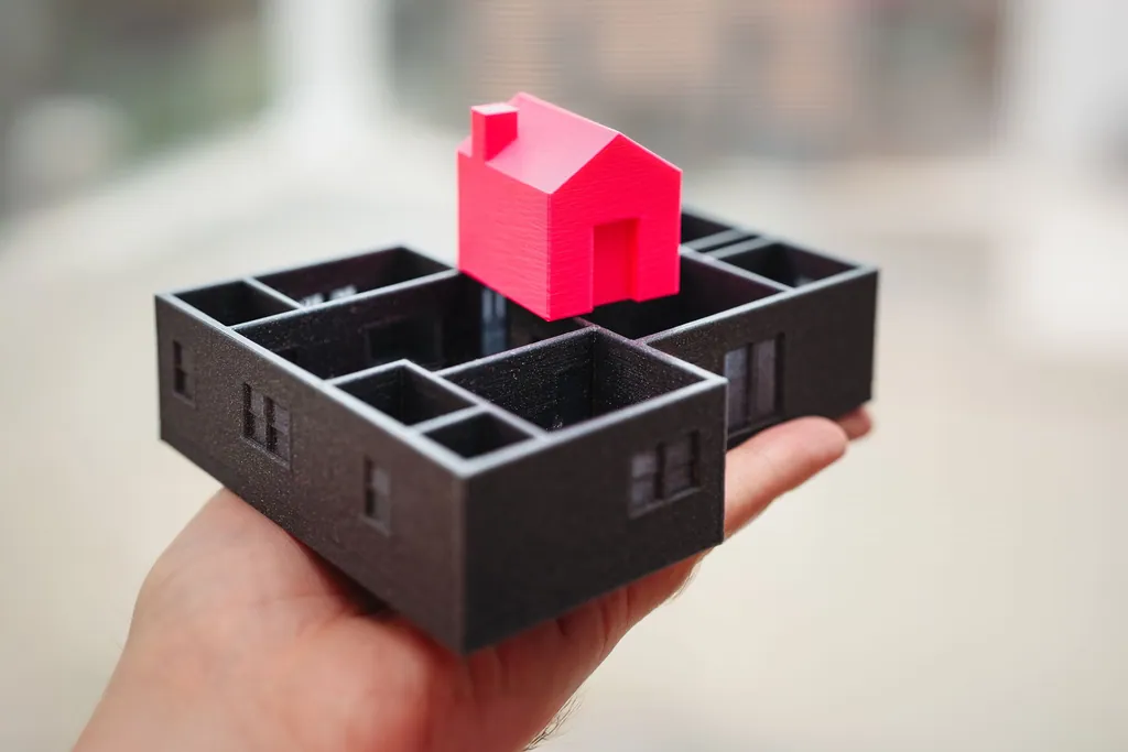 A 3D-printed house model held in one hand